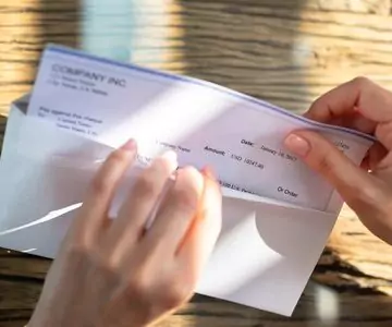 Wilson Small Business Accounting placing a payroll check in an envelope